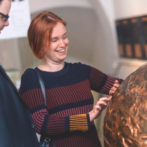 Nevidiaca návštevníčka spoznáva medený glóbus hmatom Nevidiaca návštevníčka spoznáva medený glóbus hmatom