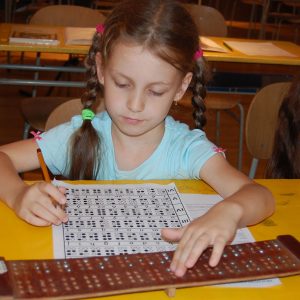 Žiačka s Braillovskou tabuľkou.
