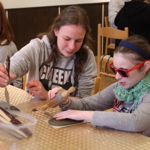 Kreatívne tvorenie. Dievča otláča vzor z dreveného valčeka do plastelíny.