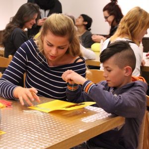 Žiak lepí vystrihnuté časti papiera na veľkonočný pozdrav.