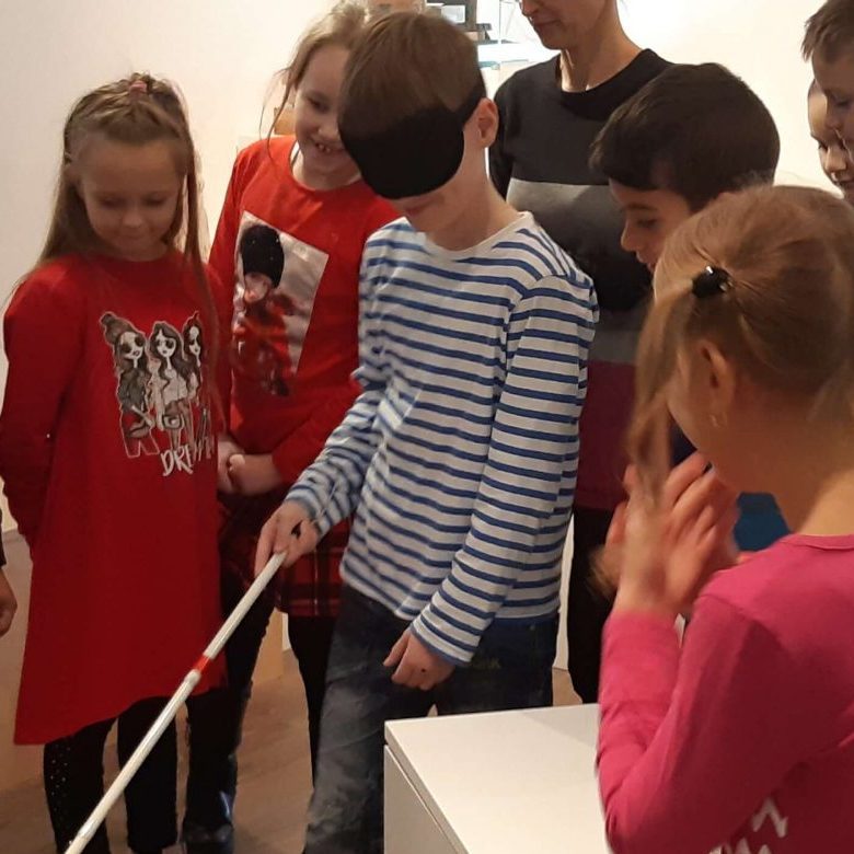 Návštevník múzea si skúša chôdzu s bielou palicou.