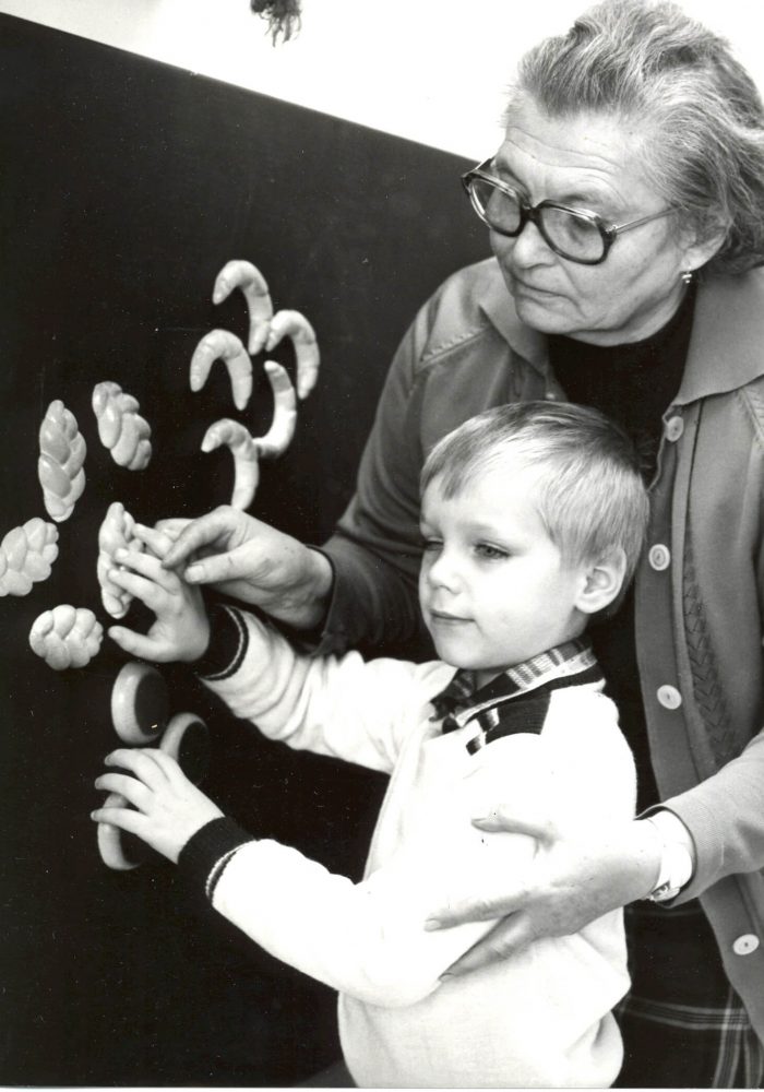 Pani Repaská s nevidiacim žiakom pri tabuli vyhmatávajú reliéfne tvary pečiva.