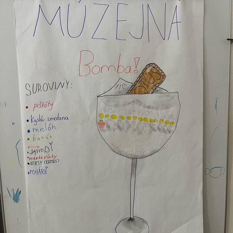 Múzejná bomba. Suroviny: piškóty, kyslá smotana, melón, banány, cukor, jahody, mandarínky, keksy (lotus), poháre.