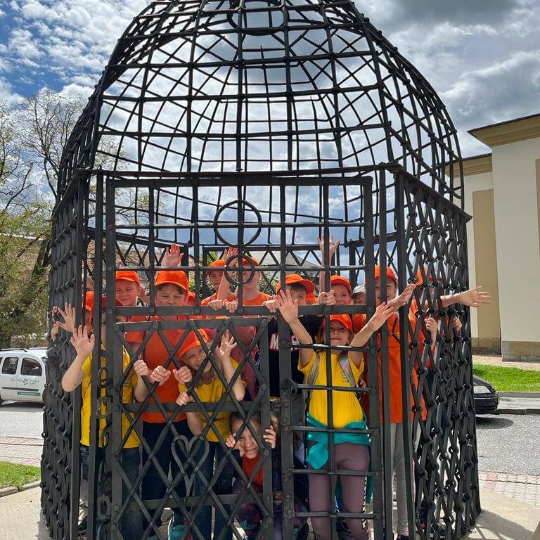 Malí múzejníci v klietke hanby na námestí.