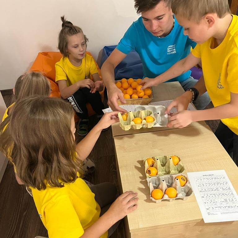 Malí múzejníci si skúšajú vyskladať písmena v Braillovom písme.