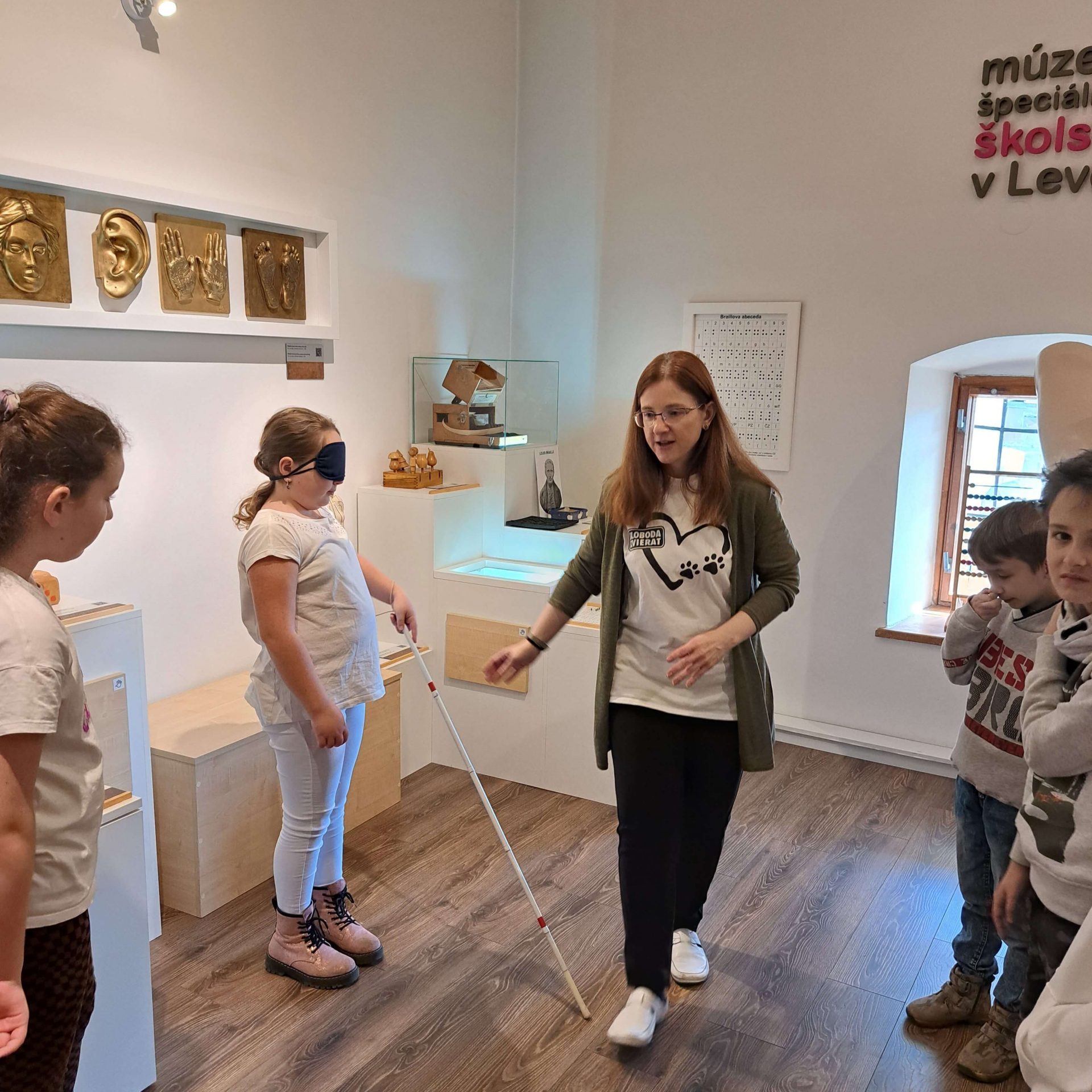 Lektorka Lucka pomáha návštevníčke múzea s chôdzou s bielou slepeckou palicou.