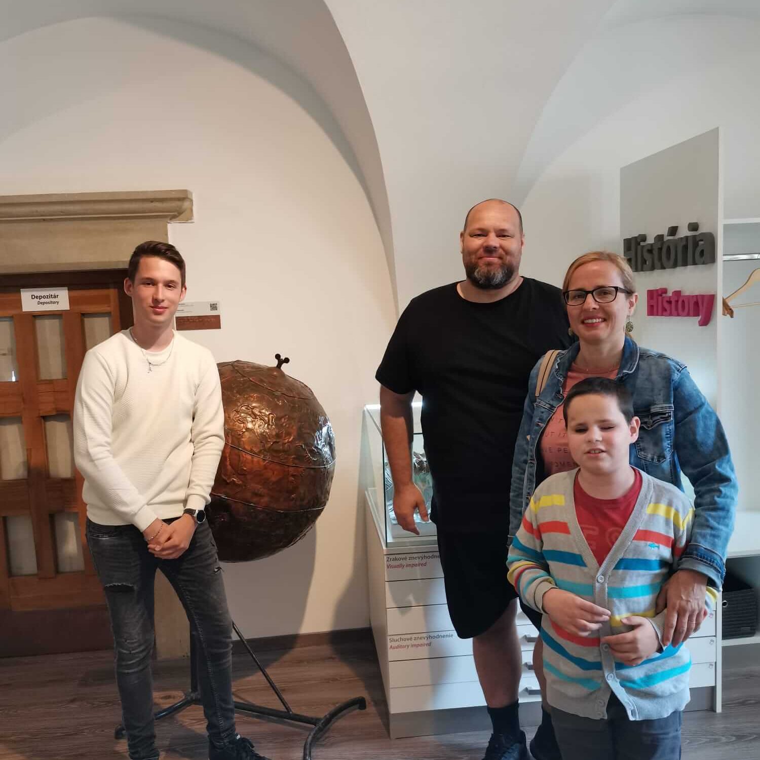 Návštevníci múzea pred medeným ručne tepaným glóbusom.