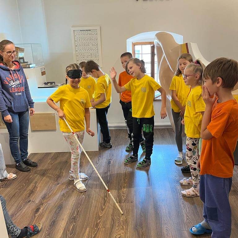 Návštevníci skúšajúci chôdzu s bielou palicou.