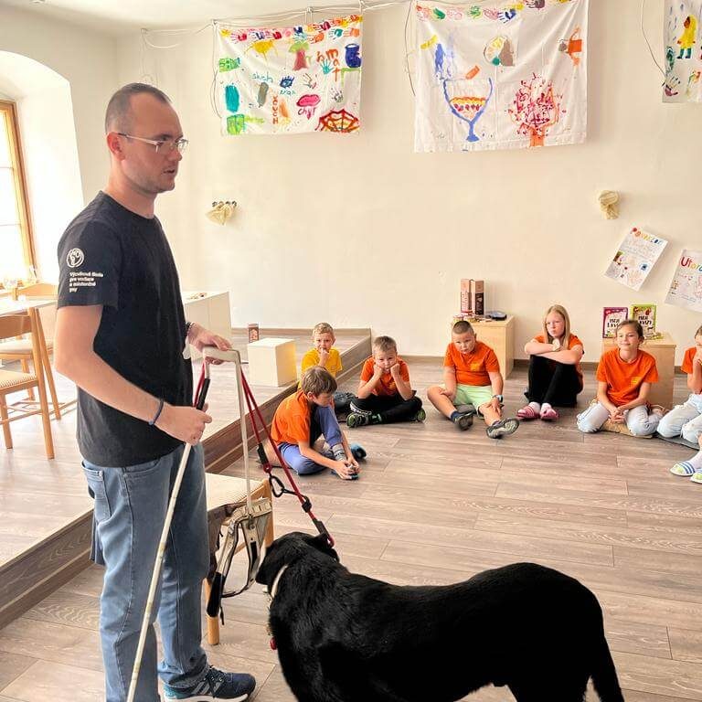 Človek s bielou slepeckou palicou a vodiacim psom v Múzeu špeciálneho školstva v Levoči.