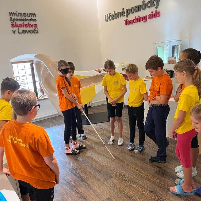 Účastníci programu Zázračná biela palica skúšajúci si chôdzu za pomoci slepeckej palice v Múzeu špeciálneho školstva v Levoči.