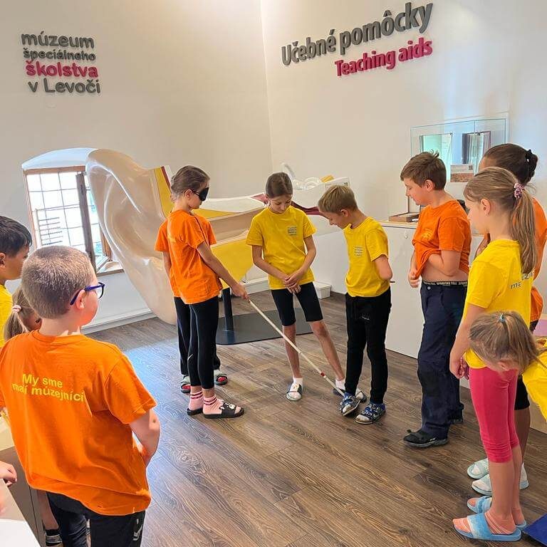 Účastníci programu Zázračná biela palica skúšajúci si chôdzu za pomoci slepeckej palice v Múzeu špeciálneho školstva v Levoči.