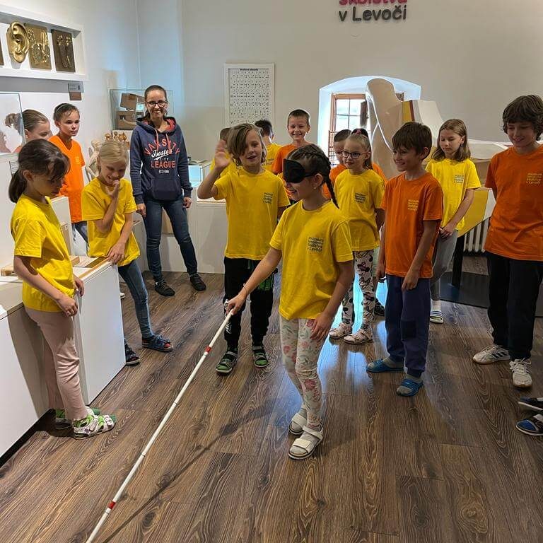 Účastníci programu Zázračná biela palica skúšajúci si chôdzu za pomoci slepeckej palice v Múzeu špeciálneho školstva v Levoči.