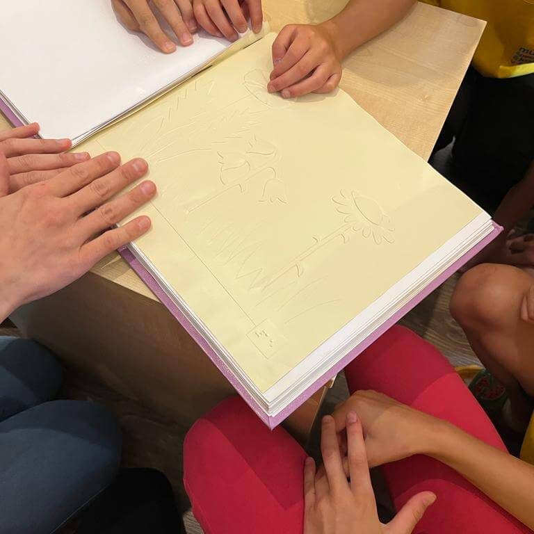 Návštevníci Múzea špeciálneho školstva v Levoči skúšajúci čítanie zo šlabikára pre nevidiacich.