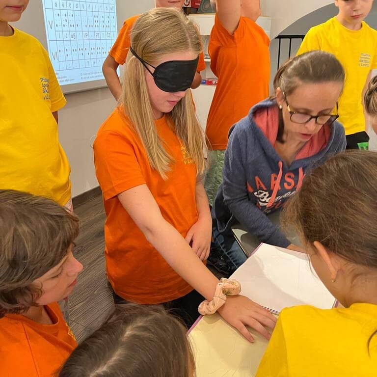 Návštevníci Múzea špeciálneho školstva v Levoči skúšajúci čítanie zo šlabikára pre nevidiacich.