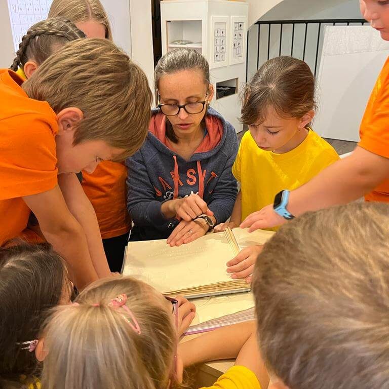 Návštevníci Múzea špeciálneho školstva v Levoči skúšajúci čítanie zo šlabikára pre nevidiacich.